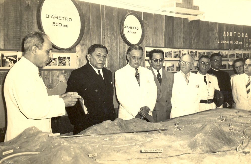 Homens em volta de uma maquete de saneamento